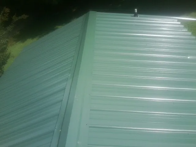 New green metal panels meeting at the ridge of a roof — Flat Roof Repair work by our crew in Prospect