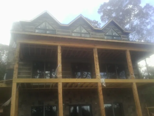 Dormers and porch framing on a large log home under construction — Roof Coating work by our crew in Prospect